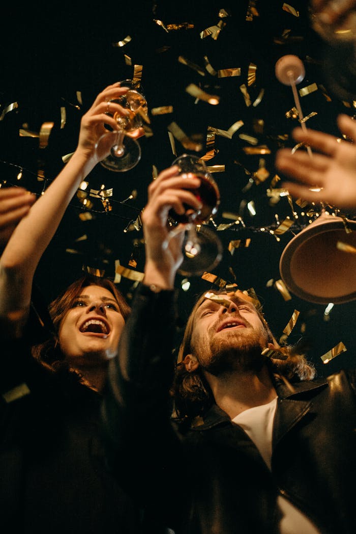 Group of friends enjoying New Year's Eve party with confetti and drinks.